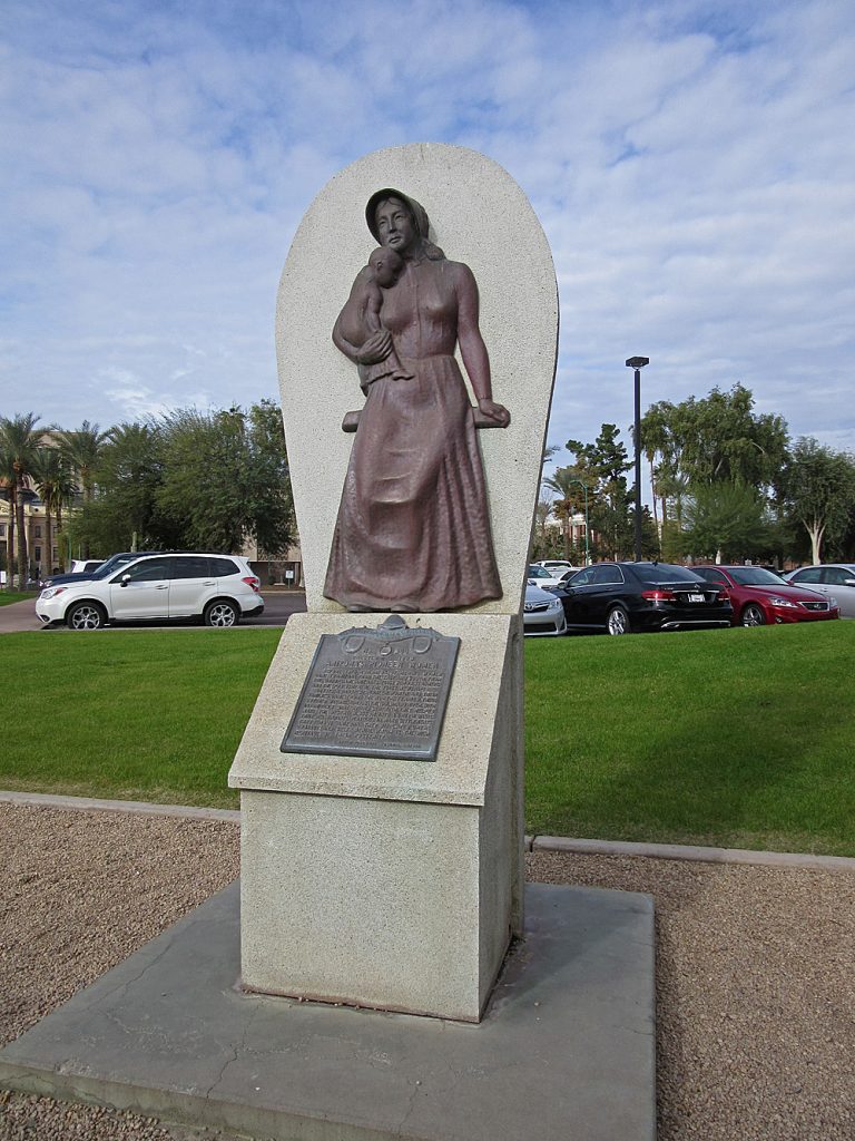 Bronze relief sculpture of a woman on semicircular concrete backdrop and base