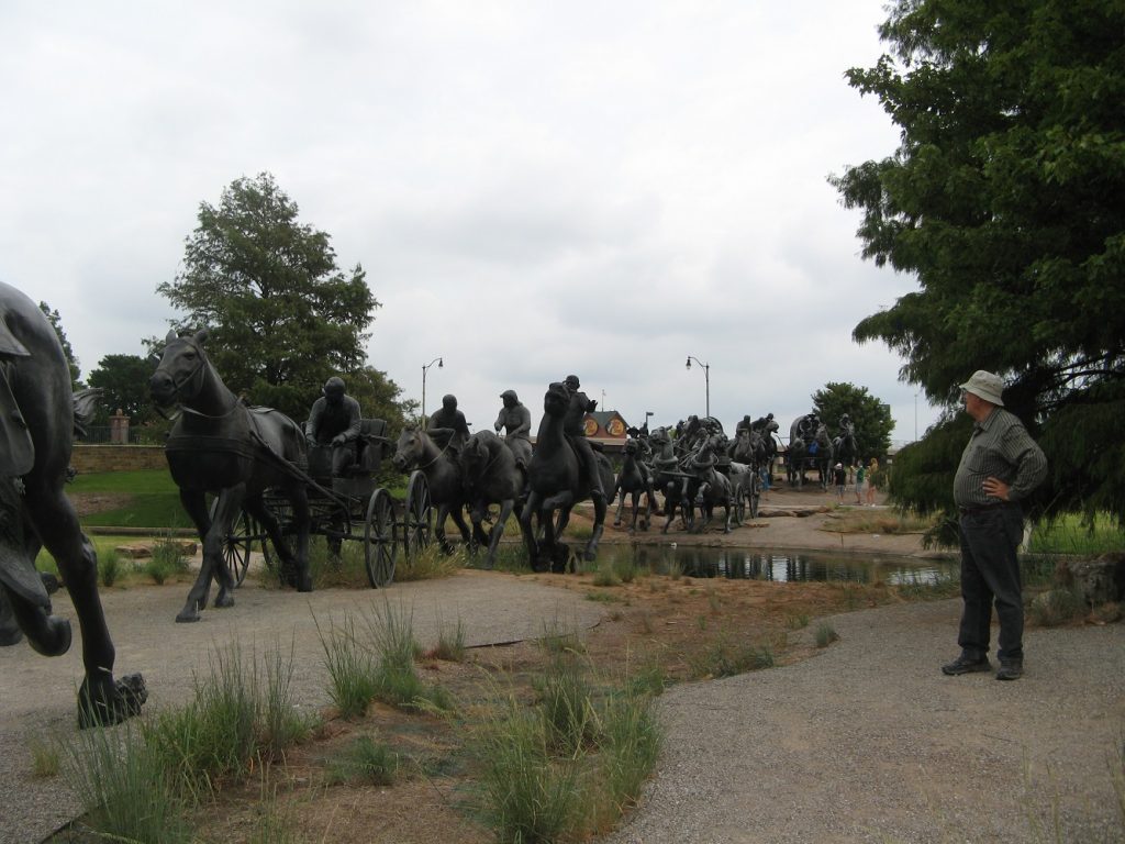 Bronze statues of people riding horses and driving wagons.