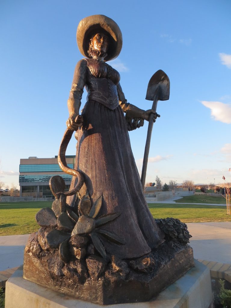 Statue of a woman holding a shovel and headless snake